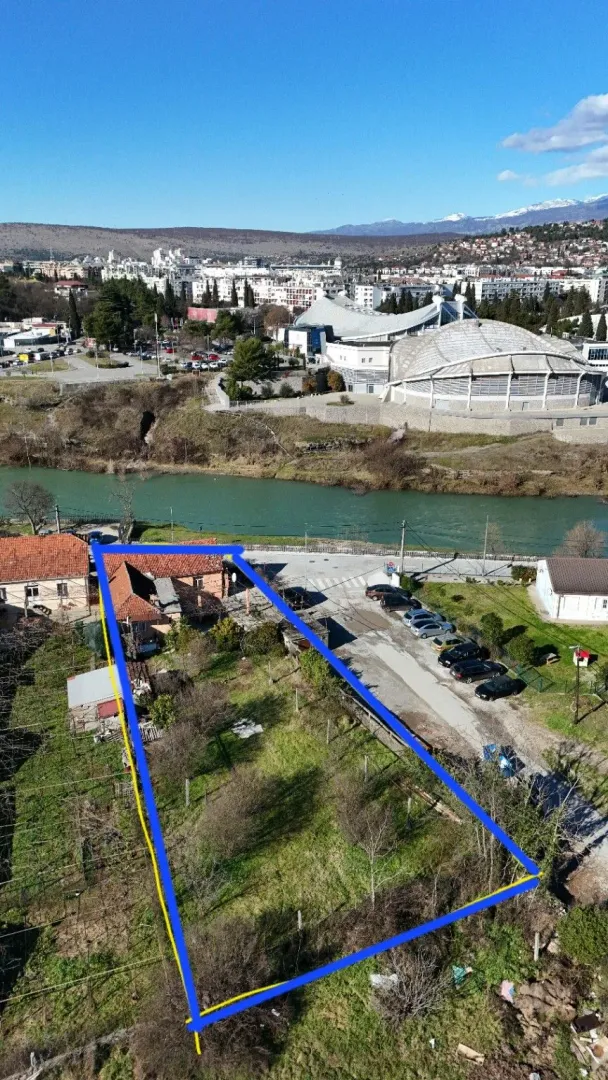 Pogled iz vazduha na parcelu sa ucrtanim granicama, rijekom i gradom u pozadini.