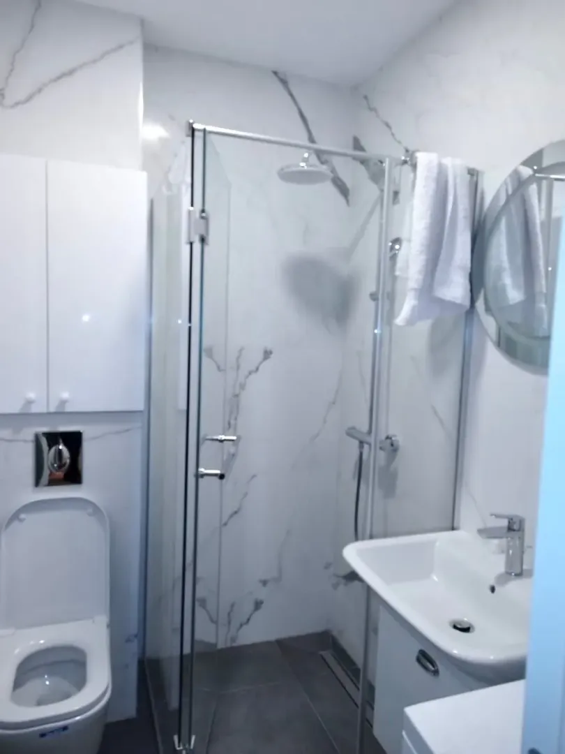 Moderne kupatilo sa tuš kabinom, umivaonikom i wc šoljom.