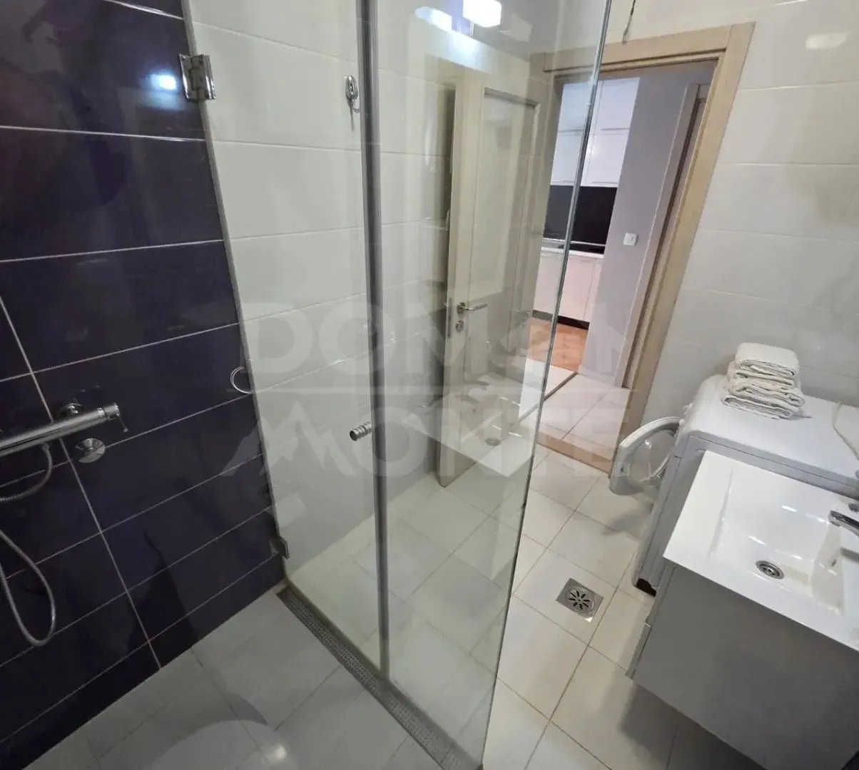 Moderno opremljeno kupatilo sa tuš kabinom i umivaonikom.