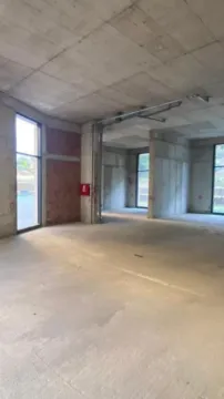 View of an empty space under construction with concrete pillars and windows. - image 3