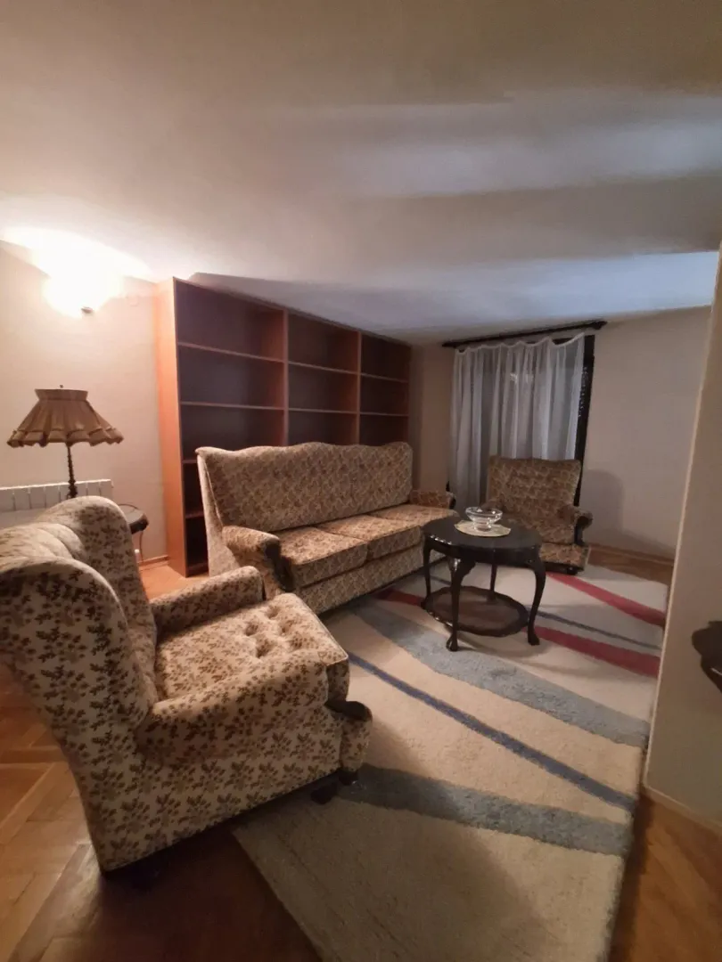Living room with a sofa set, large bookshelf, and a rug.