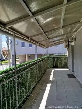Natkriveni balkon sa metalnom ogradom i pogledom na okolinu. - image 12