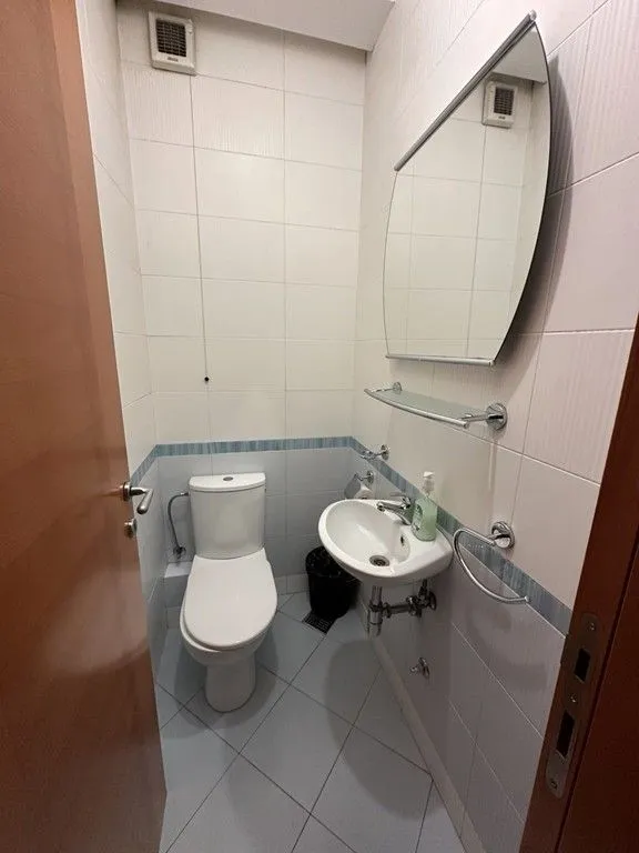 Manje kupatilo sa toaletom, umivaonikom i ogledalom.