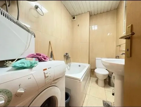 Smaller bathroom with a bathtub, washbasin, toilet, and washing machine. - image 7
