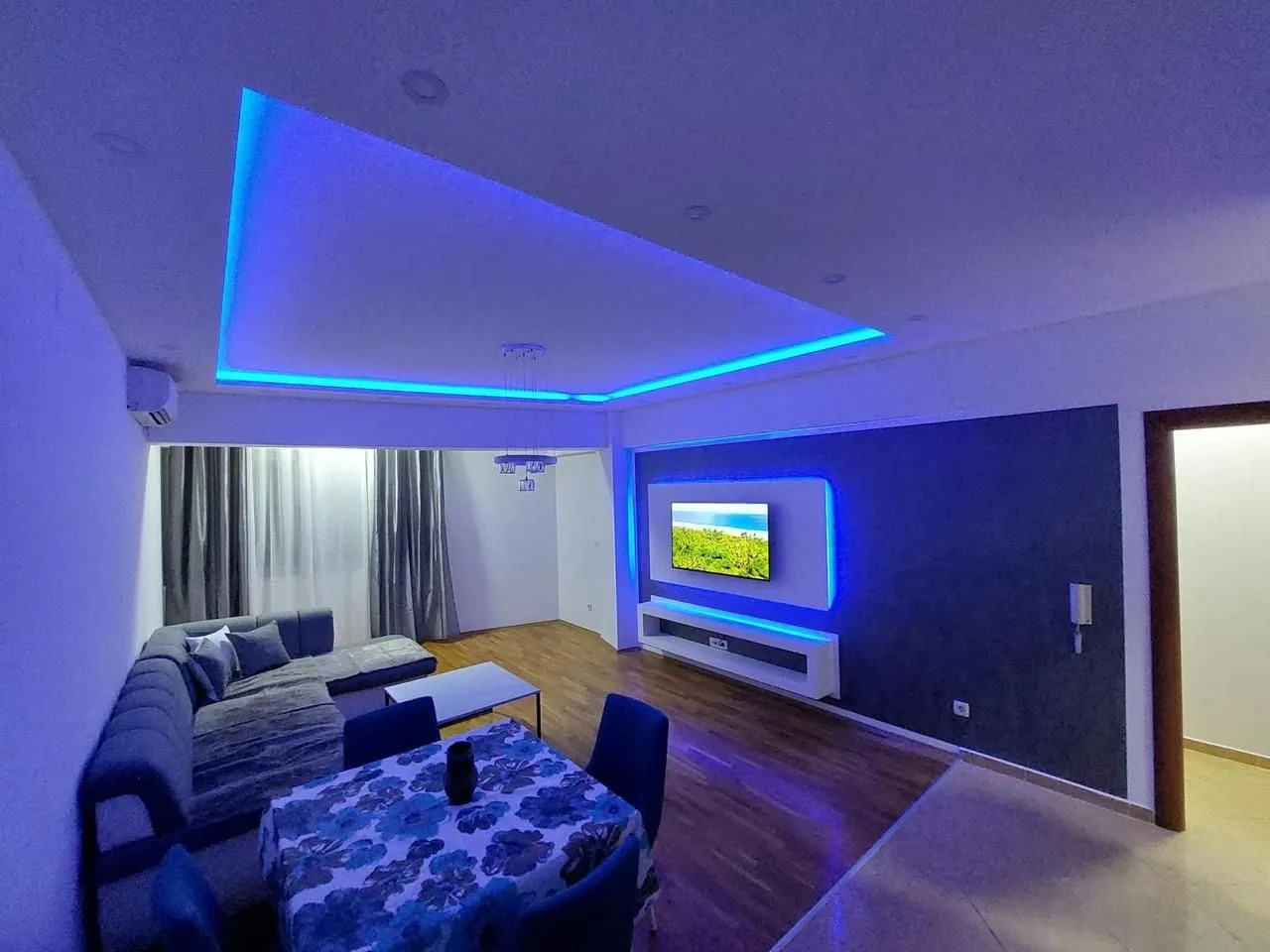Living room with a sofa, dining table, and modern lighting.