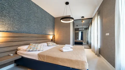 Moderna spavaća soba sa bračnim krevetom, drvenim uzglavljem i ugradnim ormarom sa ogledalom. - image 13