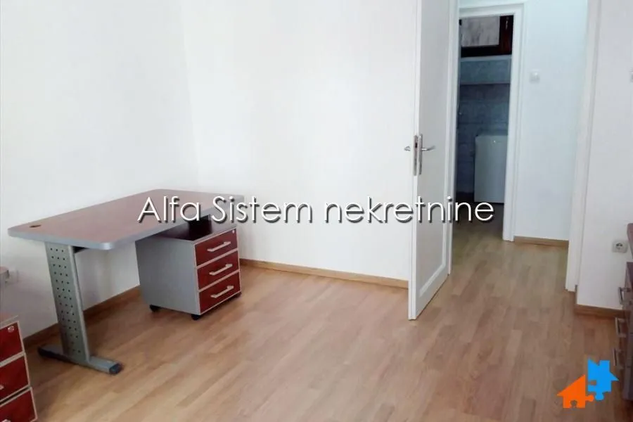 Small room with a desk and laminate flooring.