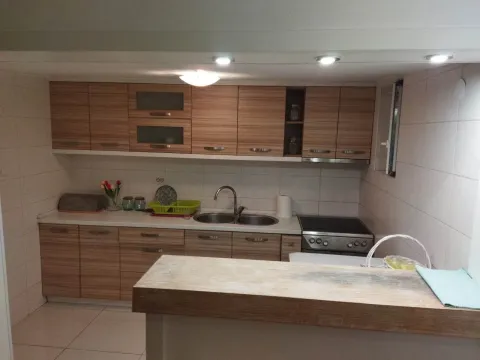 Kuhinja sa drvenim elementima, sudoperom i šankom u prvom planu. - image 4