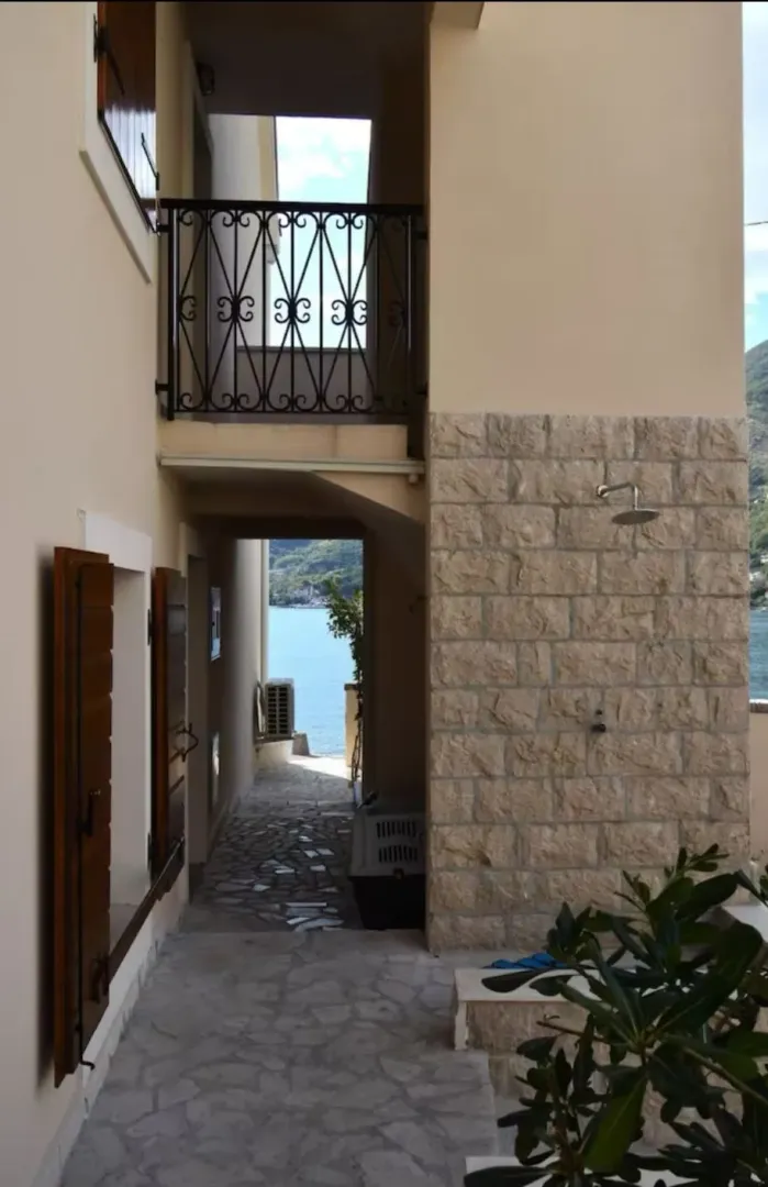 Eksterijer kuće sa kamenim zidom i pogledom na more.