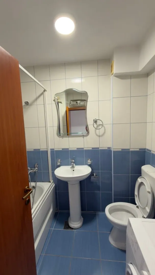 Smaller bathroom with a bathtub, washbasin, and toilet tiled in blue and white tones.