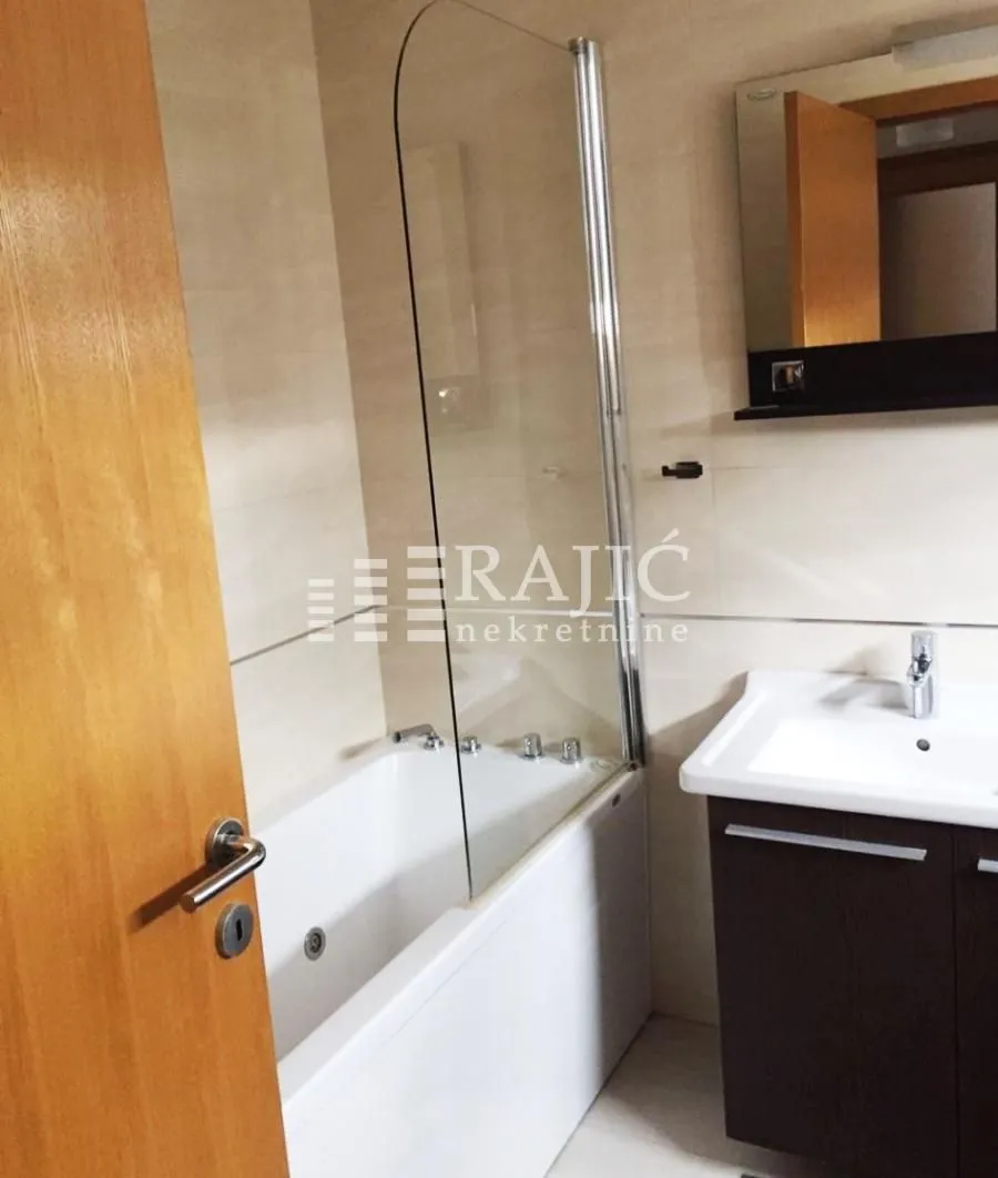 Smaller bathroom with a bathtub, glass screen, and washbasin.