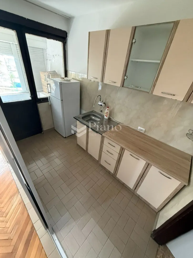 Smaller kitchen with kitchen cabinets, a sink, and a refrigerator.