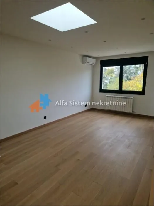 Empty room with wooden flooring, a window, and a skylight.