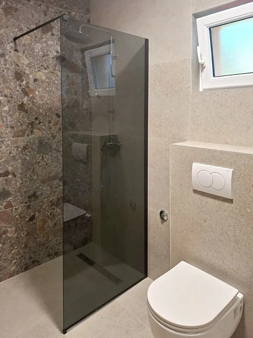 Moderno opremljeno kupatilo sa tuš kabinom i ugradnom šoljom.