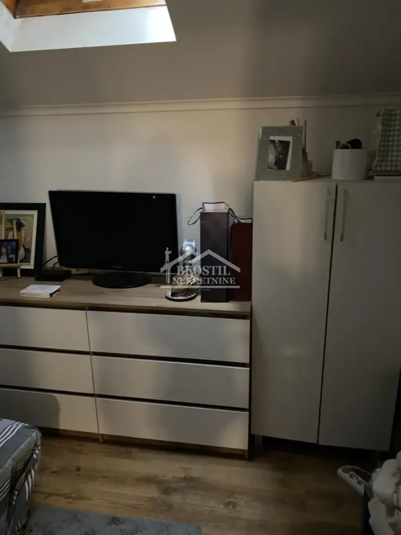 Deo sobe sa komodom, televizorom i garderoberom u potkrovlju.