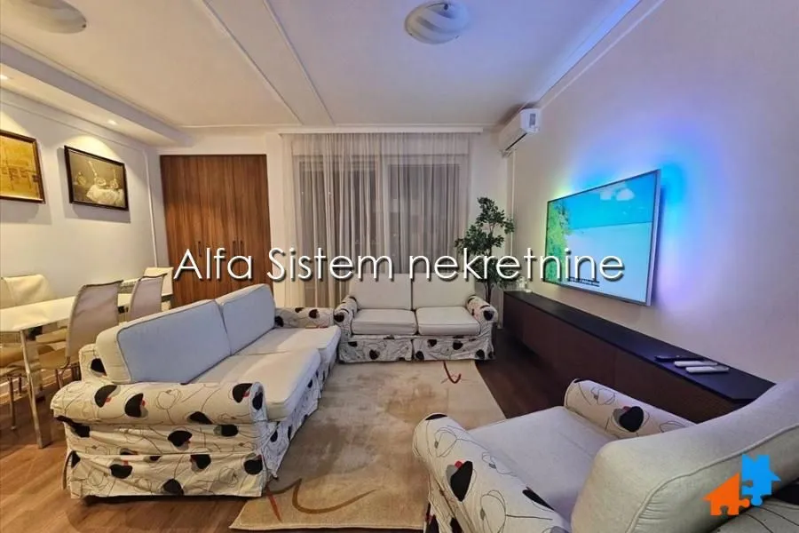 Living room with a sofa set, television and dining table.