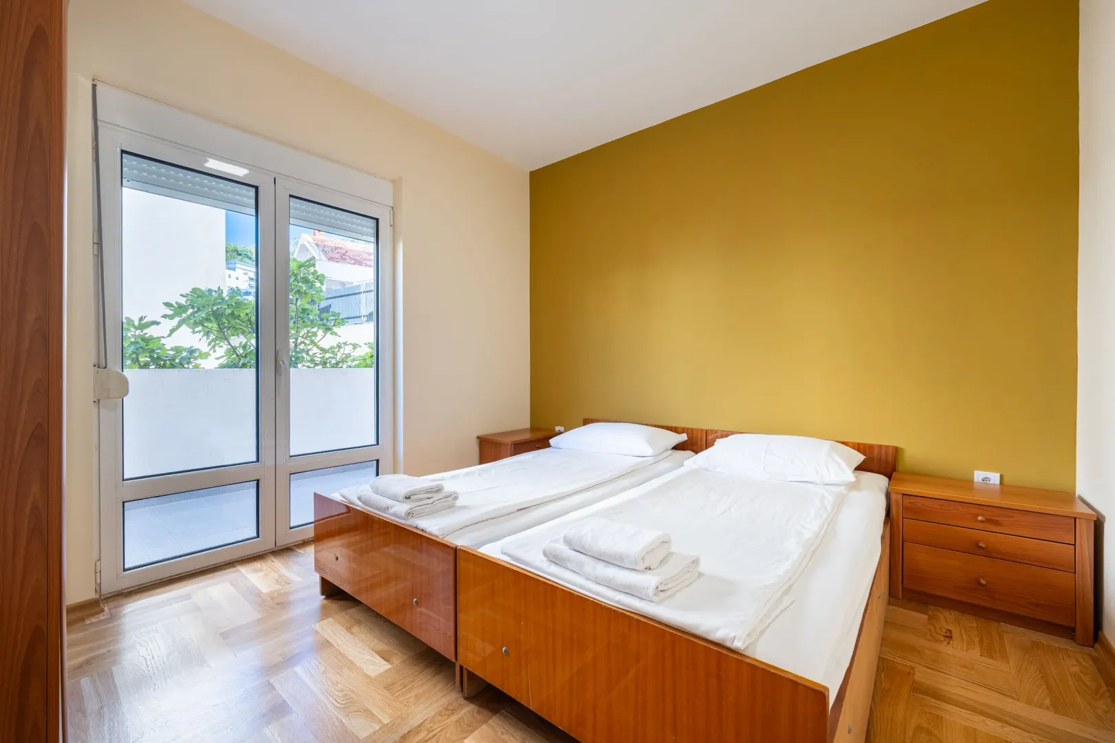 Furnished bedroom with two single beds and balcony access.