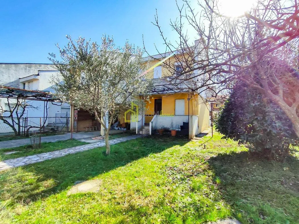 Pogled na dvorište i fasadu kuće sa zelenilom.