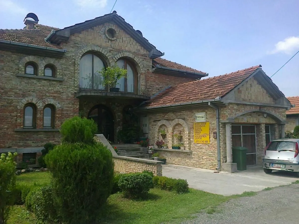 Prednji deo kuće sa dvorištem, fasadom od cigle i garažom.