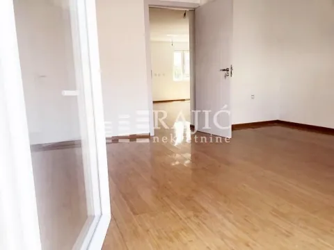 Empty room with wooden flooring and an open door leading to the hallway. - image 13