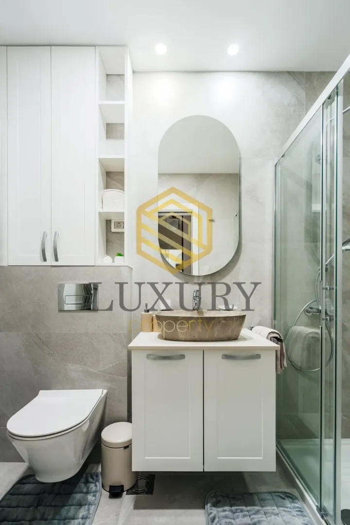 Modernly equipped bathroom with a washbasin, shower cabin, and white sanitary ware.