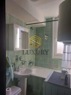Small bathroom with a bathtub, washbasin, and green tiles. - image 6
