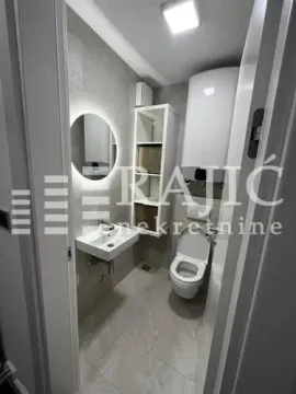 Modernly equipped bathroom with a washbasin, toilet, and water heater. - image 3