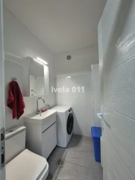 Smaller bathroom with a sink, toilet, washing machine, and mirrored cabinet. - image 8