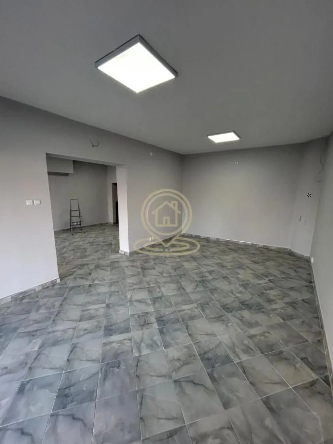 Empty room with tiled flooring and ceiling lighting under renovation.