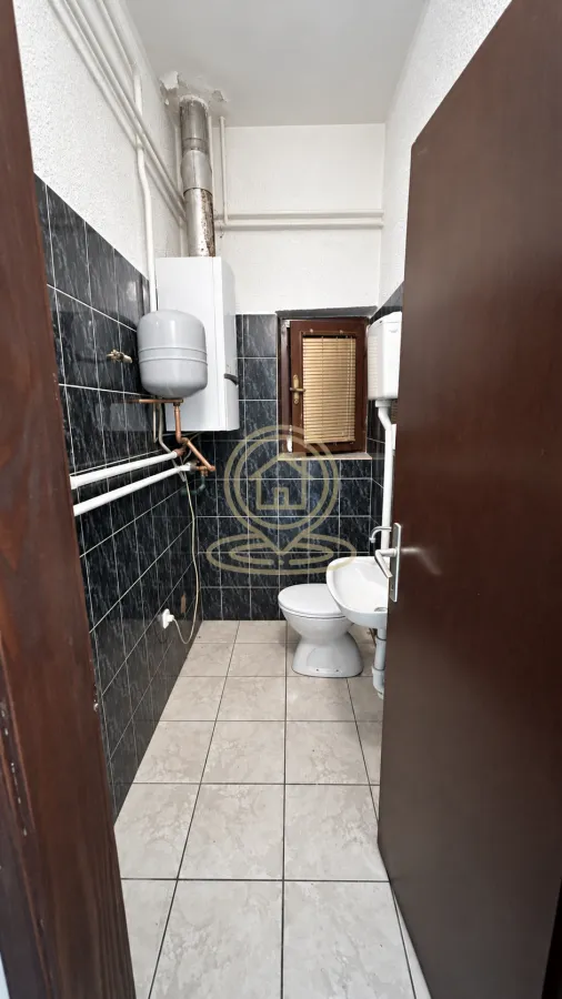 Smaller bathroom with a toilet, washbasin, and water heater.