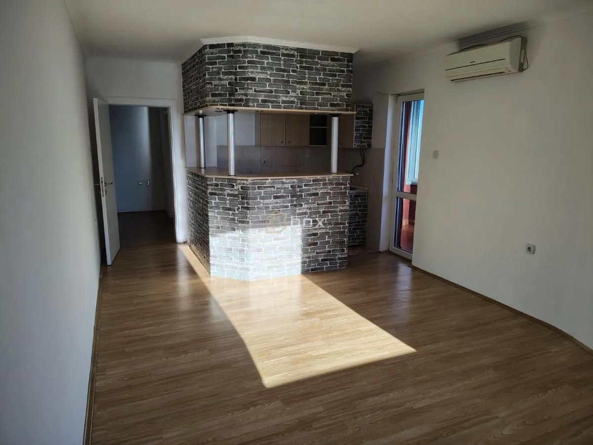 Living room with laminate flooring and a breakfast bar separating it from the kitchen.