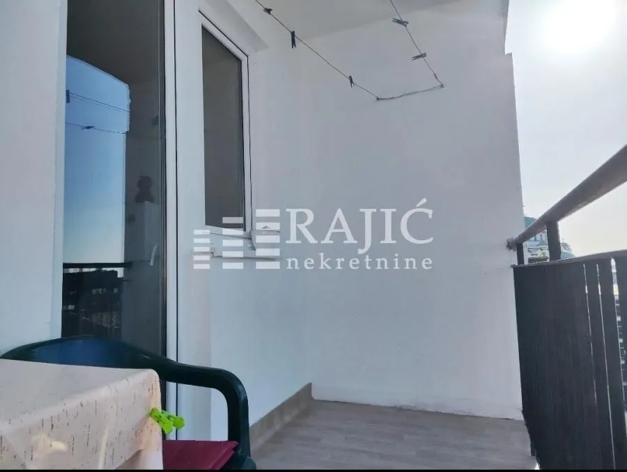 Small bright balcony with seating furniture.