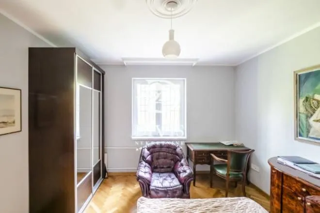 Furnished bedroom with a wardrobe, armchair, and desk.