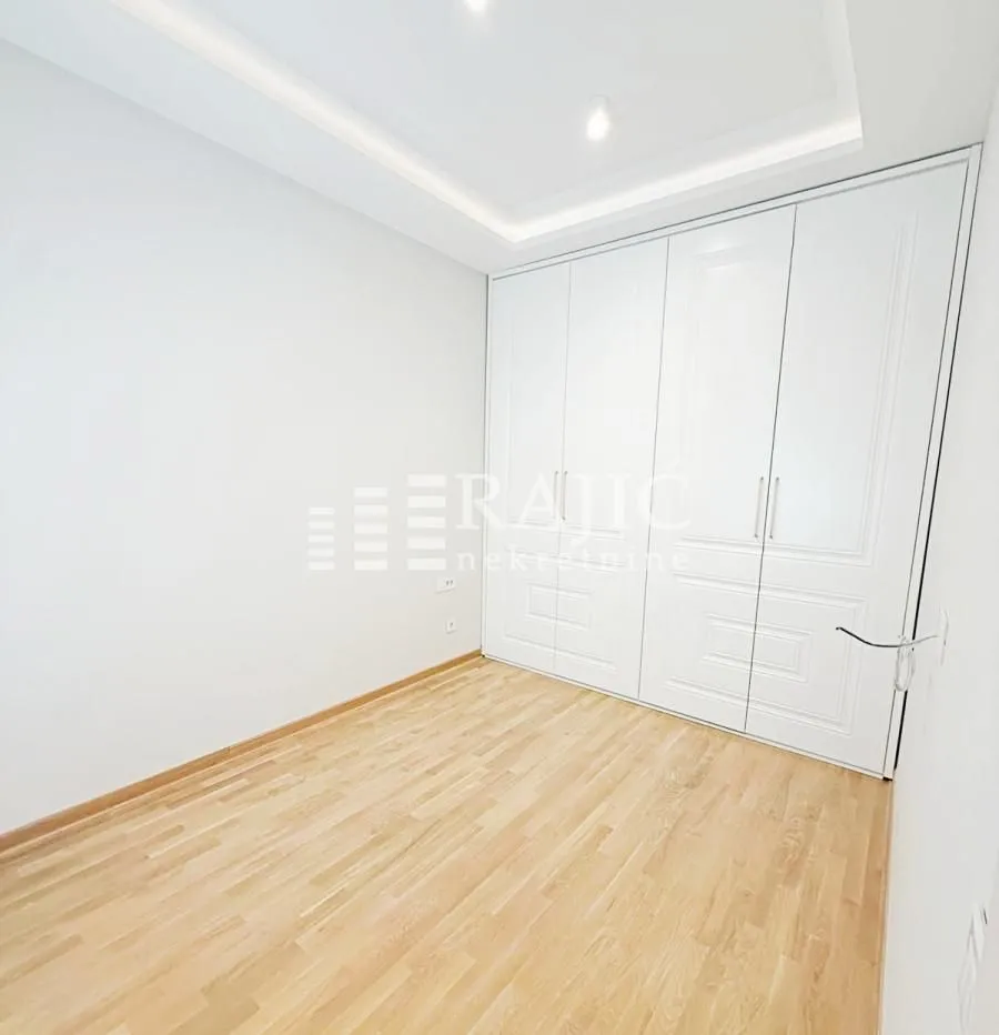 Empty bedroom with a built-in wardrobe and parquet flooring.