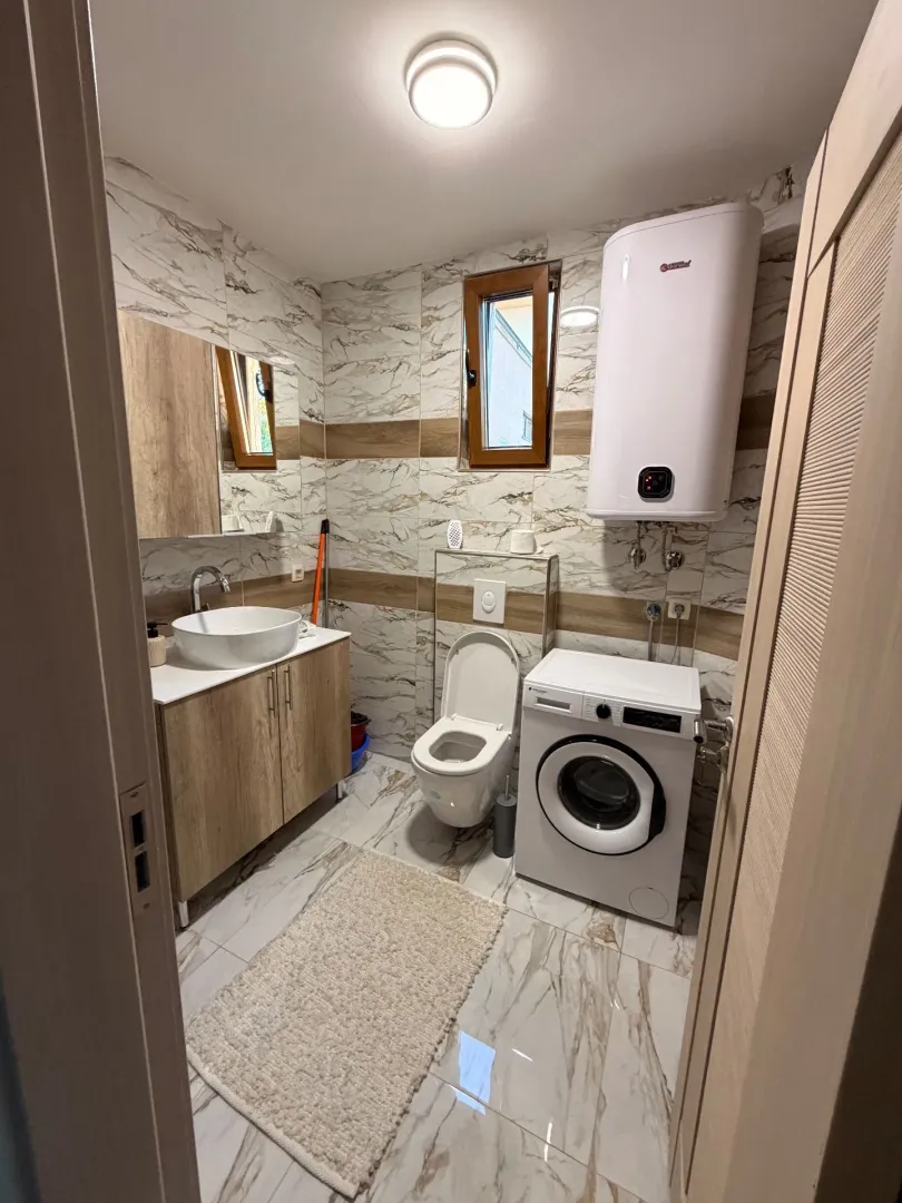 Moderno opremljeno kupatilo sa umivaonikom, wc šoljom i veš mašinom.