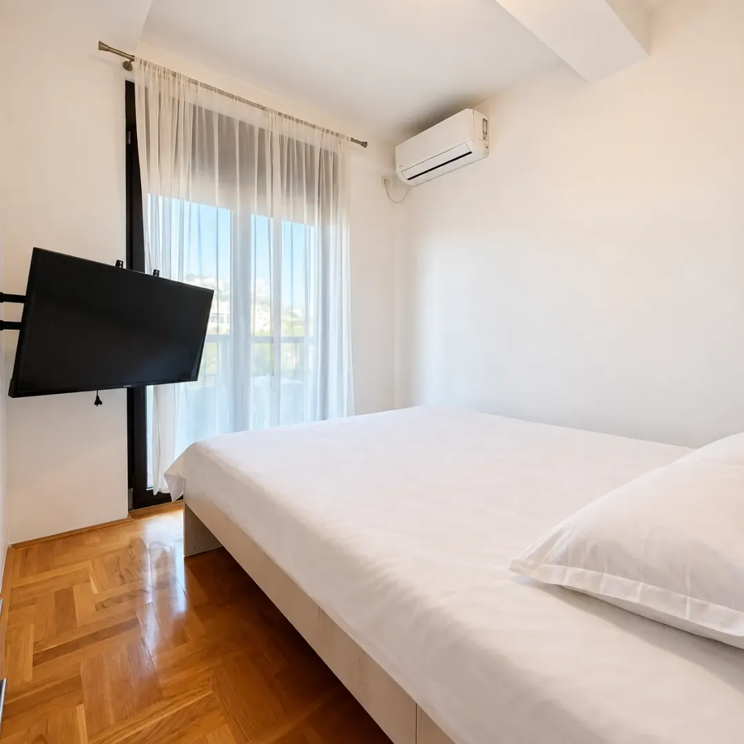 Bright bedroom with a double bed, air conditioning, and a TV.