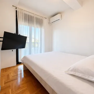 Bright bedroom with a double bed, air conditioning, and a TV. - image 3