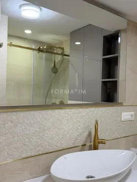 View of the sink with a gold faucet and mirror in a modern bathroom. - image 6