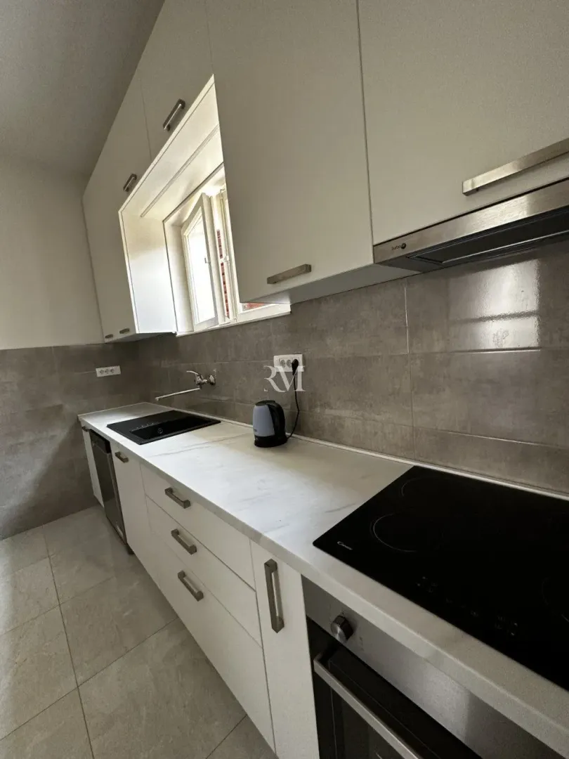 Modern white kitchen with built-in hob and sink.