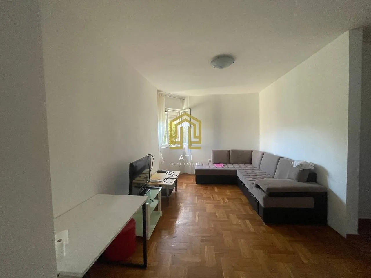 Living room with a corner sofa, TV and a desk.