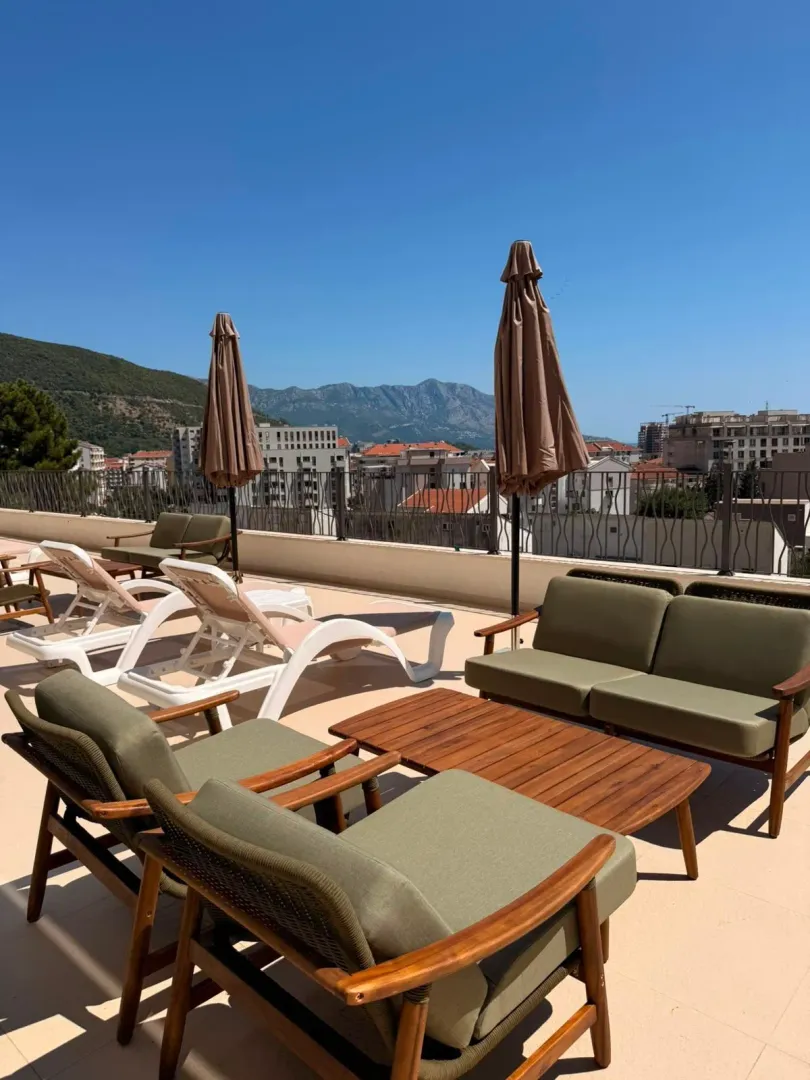 Spacious roof terrace with lounge furniture, sun loungers, and views of the city and mountains.