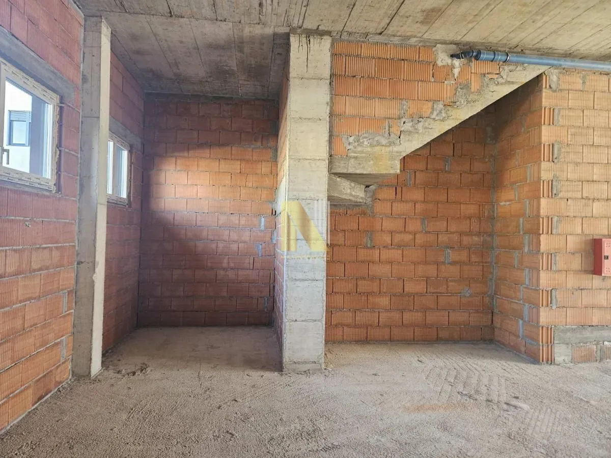 View of an unfurnished space in rough construction phase with stairs.