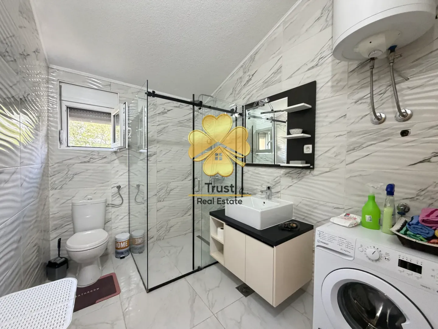 Modernly equipped bathroom with a walk-in shower, washbasin, and washing machine.