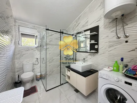 Modernly equipped bathroom with a walk-in shower, washbasin, and washing machine. - image 17