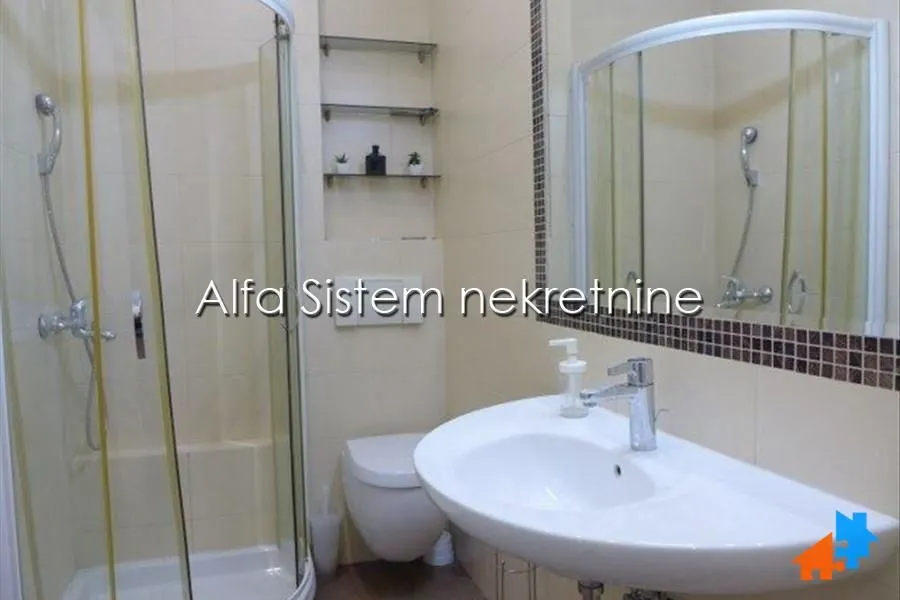 Bathroom equipped with a shower cabin, washbasin, toilet bowl, and a large mirror.