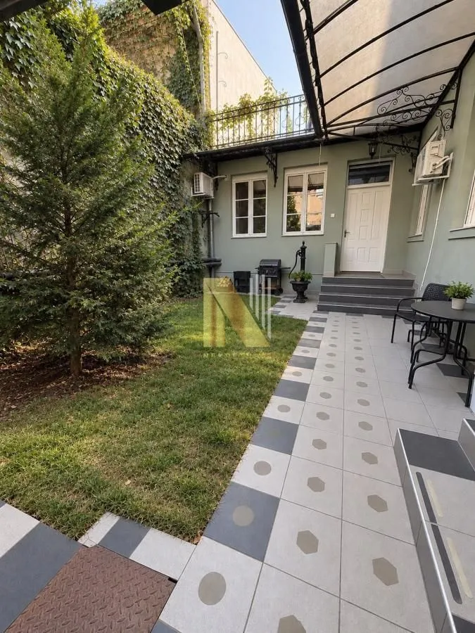 View of the landscaped courtyard and house entrance with a tiled area and lawn.