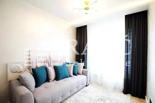 Living room with a comfortable sofa and a large window with dark curtains.