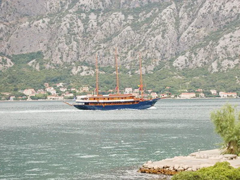 Pogled na zaliv sa brodom koji plovi i planinama u pozadini.