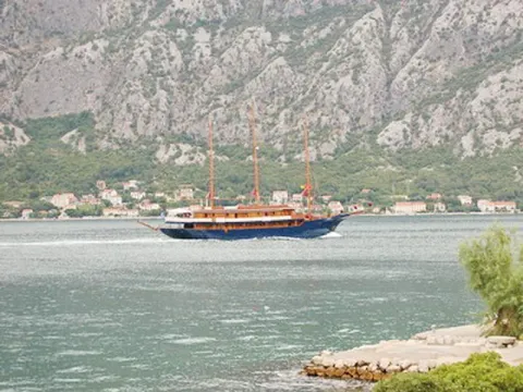 Pogled na zaliv sa brodom koji plovi i planinama u pozadini. - image 6