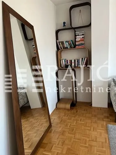 Dnevni boravak sa velikim ogledalom i zidnim policama.